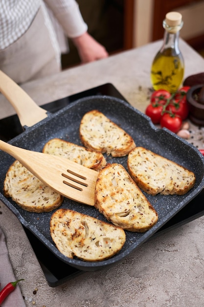 Pane affettato fritto sulla padella alla griglia in cucina domestica