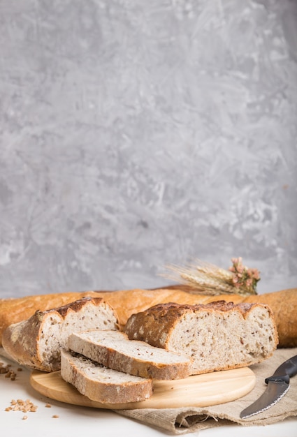 Sliced bread with different kinds of fresh baked bread on a gray concrete surface. side view, selective focus.