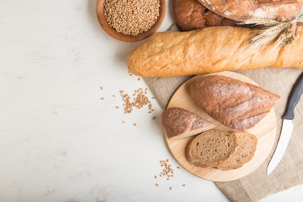 Нарезанный хлеб с различными видами свежего хлеба на белом фоне деревянные. вид сверху, копия пространства.