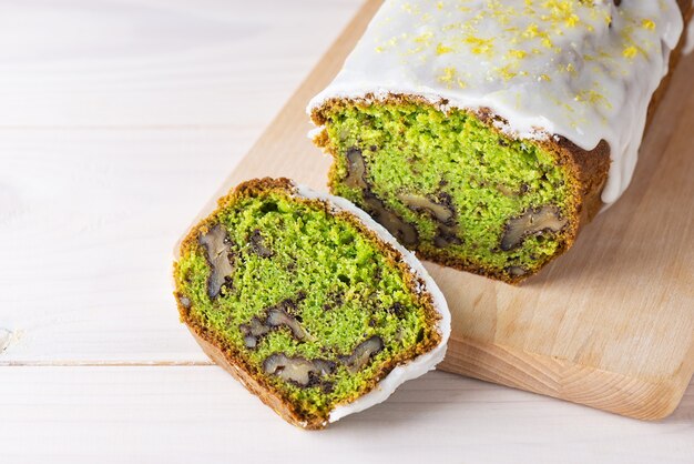 Sliced cake with spinach and walnuts on a wooden table