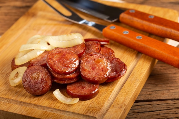 sliced calabrese sausage with onion on wooden background