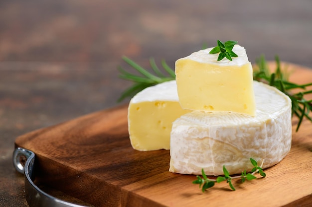 Sliced Camembert Cheese with thyme on wood plate