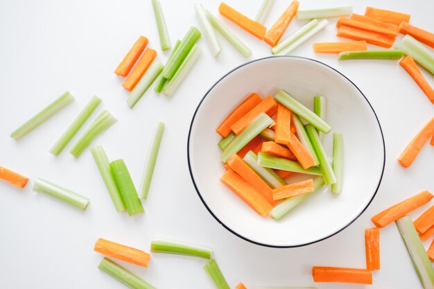 Sliced carrots and celery in a white bowl, healthy food