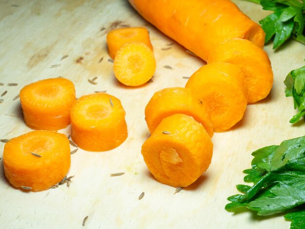 Sliced carrots on the table greens and cumin seeds soup preparation soup ingredient for a veggie lunch