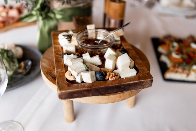 Sliced cheeses on a wooden plate in a restaurant on the table