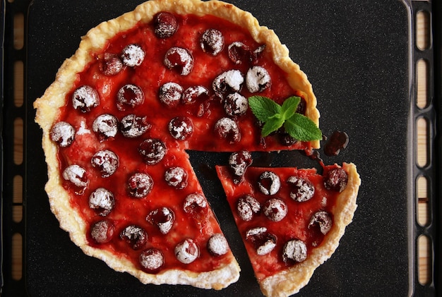 Sliced cherry pie in oven tray