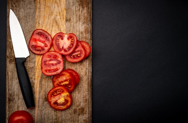 Sliced cherry tomatoes with knife on wooden board on background with copyspace. Healthy organic pomodoro vegetable for bruschetta view from above