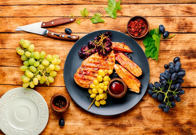 Sliced chicken breast with grapes on rural wooden table