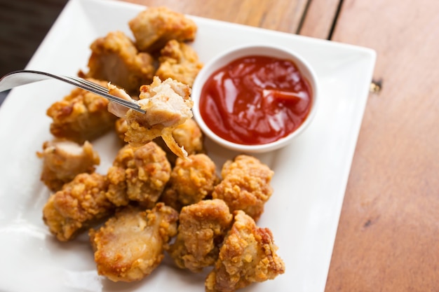 Sliced chicken fried served with ketchup on white plate. Crunchy snack. 