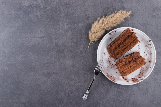 Sliced chocolate cake with fork placed on a stone table .