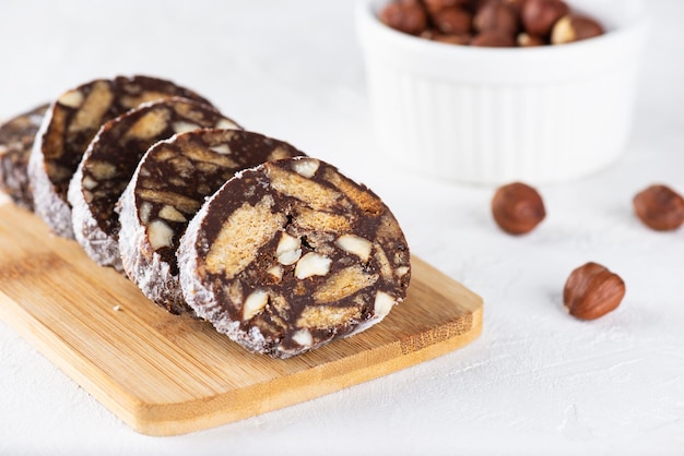 Sliced chocolate salami sausage with hazelnut on a wooden board without sugar gluten and lactose