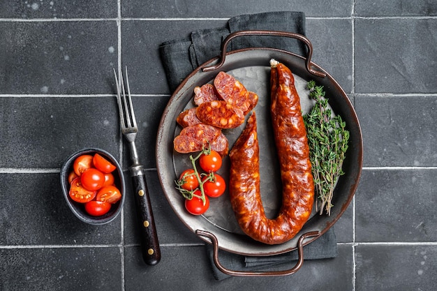 Фото Нарезанная колбаса chorizo кусочки сухого свинины с травами и специями черный фон верхний вид