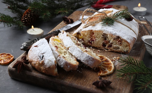 Sliced Christmas stollen with dry fruits, berries and nuts on wooden board. Traditional German treats. Close-up