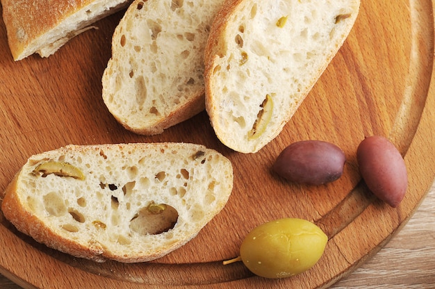 Sliced ciabatta bread on a round Board, olives