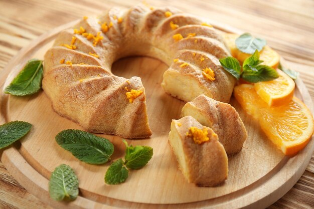 Sliced citrus cake with mint leaves on wooden board