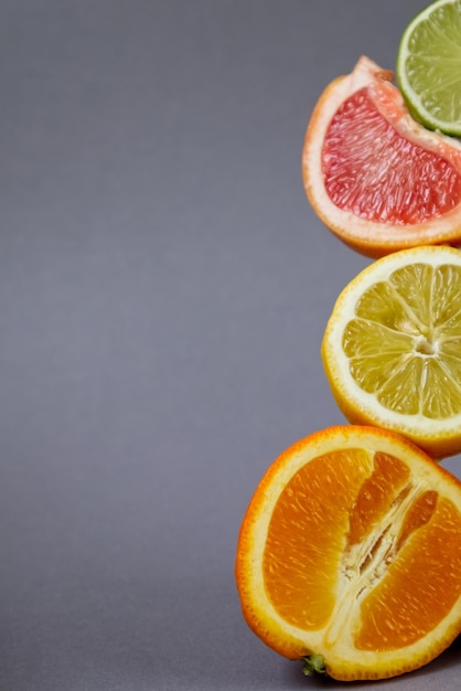 Sliced citrus fruits in different sizes and colors close up on gray background