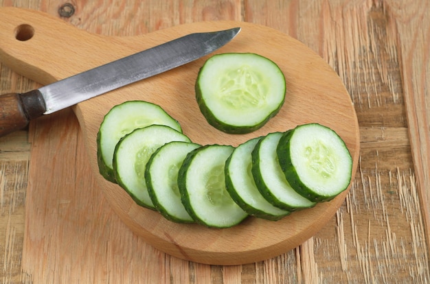 Sliced cucumber and knife on old wooden table