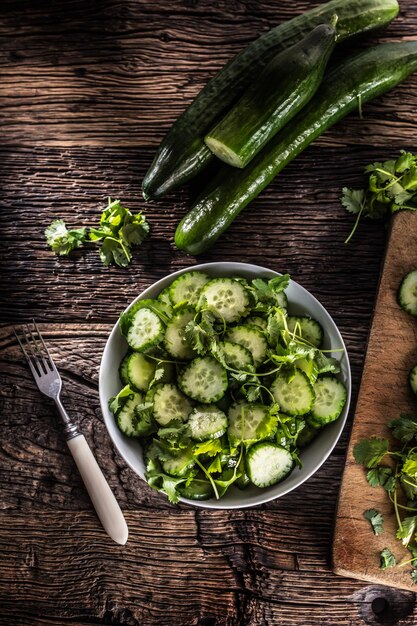 Sliced cucumber on a plate with parsley herb on rustic oak wood