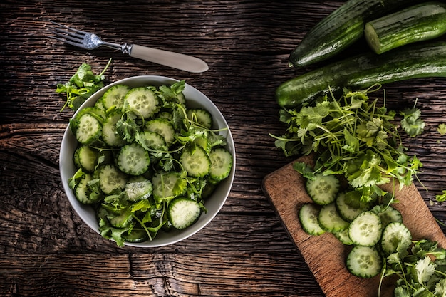 Sliced cucumber on a plate with parsley herb on rustic oak wood.