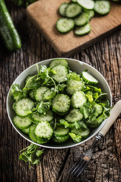 Sliced cucumber on a plate with parsley herb on rustic oak wood.