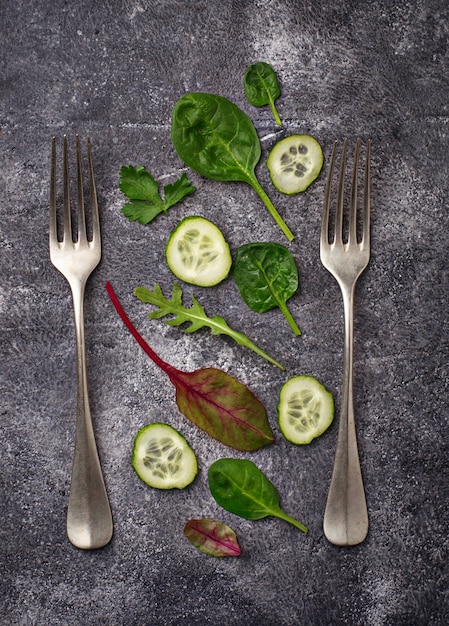 スライスしたキュウリとサラダミックス。緑の野菜の背景、健康食品のコンセプトです。上面図