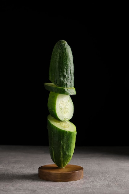 Sliced cucumber stands wooden stand black background