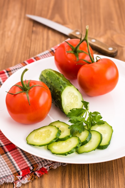 Sliced cucumber and tomatoes on a plate on a wooden table