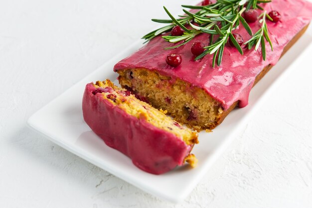 Sliced cupcake with cranberries and rosemary on a white plate