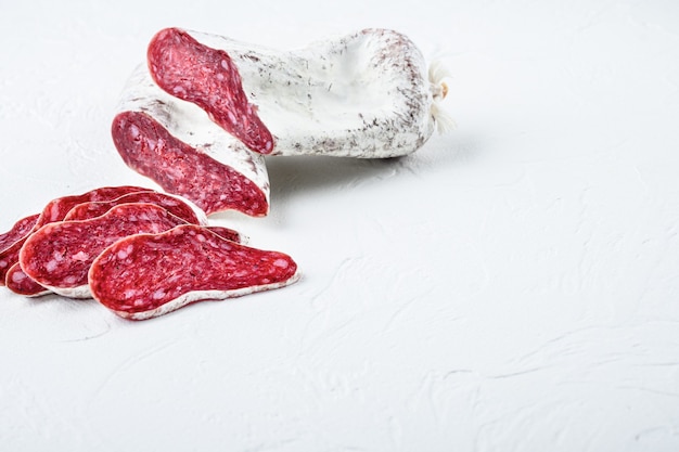 Sliced cuts of longaniza, dry cured spanish  sausage on white textured background with space for text.