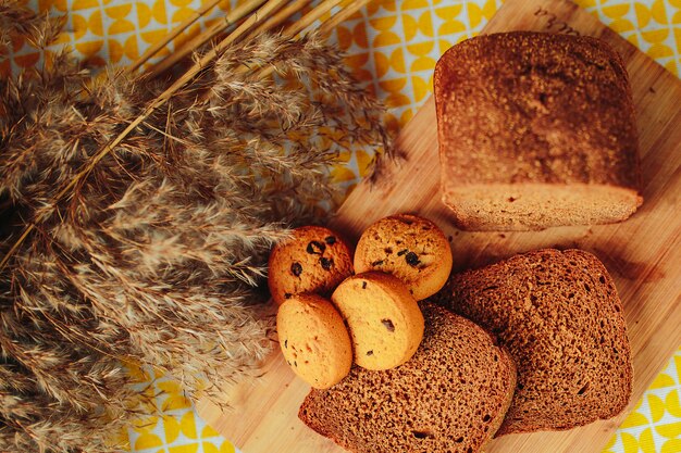 Sliced dark bread and cereal biscuits on wooden board. Healthy nutrition, healthy food on the table with dried flowers around.