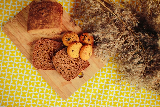 Sliced dark bread and cereal biscuits on wooden board. Healthy nutrition, healthy food on the table with dried flowers around.