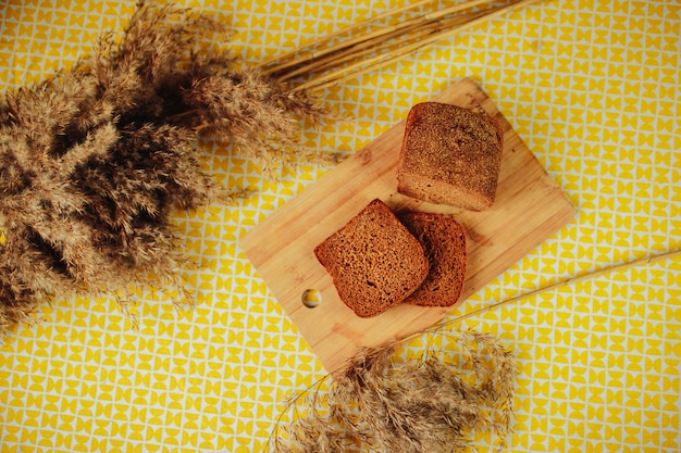 Pane scuro affettato sul bordo di legno. nutrizione sana, cibo sano sul tavolo con fiori secchi.