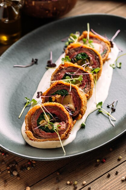 Sliced deep fried meat roll with spinach cheese and sauce