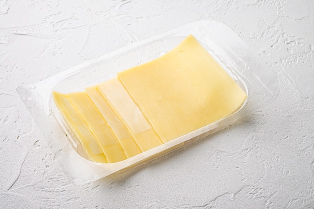 Sliced delicious edam cheese set, in plastic pack, on white stone  background