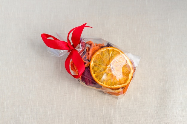  Sliced and dried apple, orange, carrot and beetroot in gift package on textile background. 