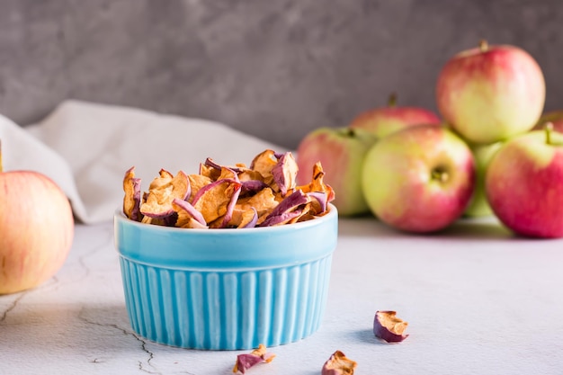 Sliced dried apples in a bowl and fresh fruit on the table Homemade snack