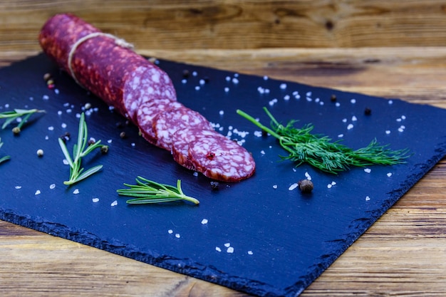 Sliced dry smoked salami sausage on a slate board