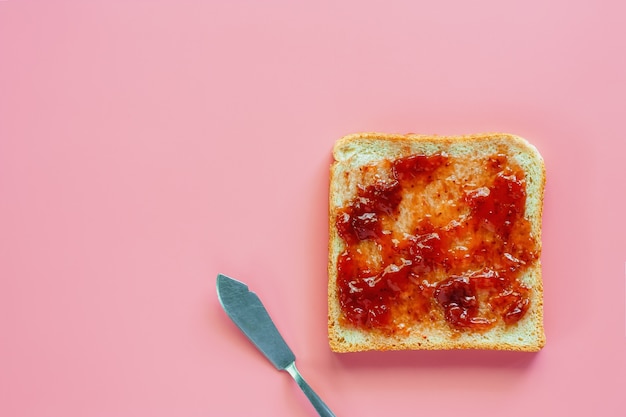 Photo sliced fine whole wheat bread with strawberry spread on pink background