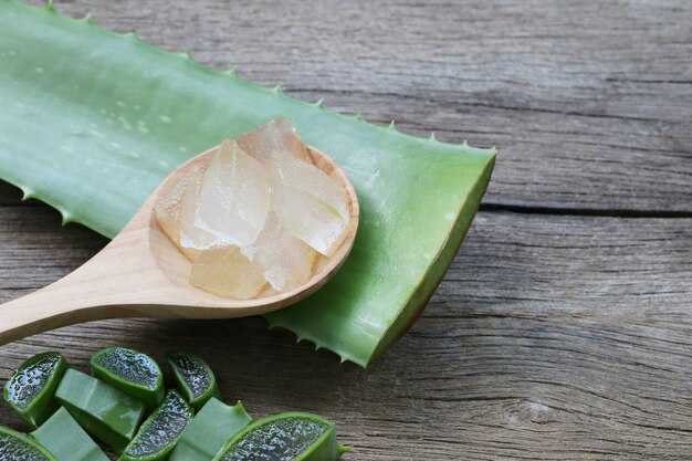 Aloe vera fresca affettata in cucchiaio di legno sul pavimento di legno marrone.