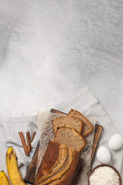 Sliced fresh banana bread with ingredients on light background