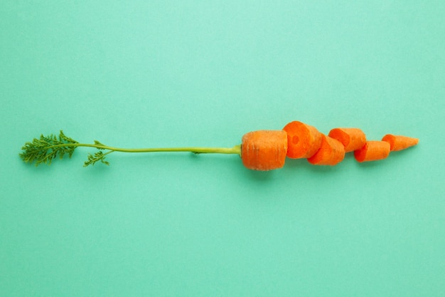 Sliced fresh carrots on mint background Top view