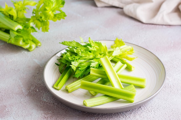 新鮮なセロリの茎をスライスし、テーブルの上の皿に葉を載せて食べる準備をします。ベジタリアンフード