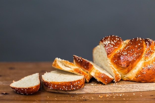 Sliced fresh challah bread on the wood table.