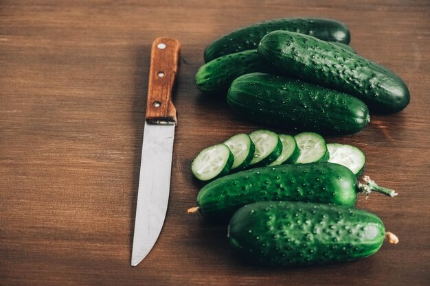 Sliced fresh green cucumbers with a knife on a wooden background