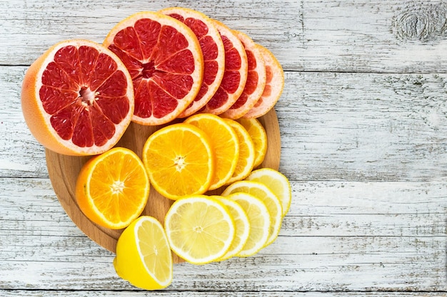 Sliced fresh lemons grapefruits oranges on a wooden cutting board with a knife