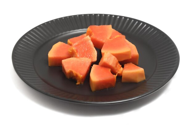 Sliced fresh organic papaya delicious fruit in a black plate isolated on white background