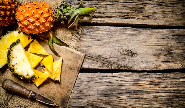 Sliced fresh pineapple with a knife on a chopping Board.