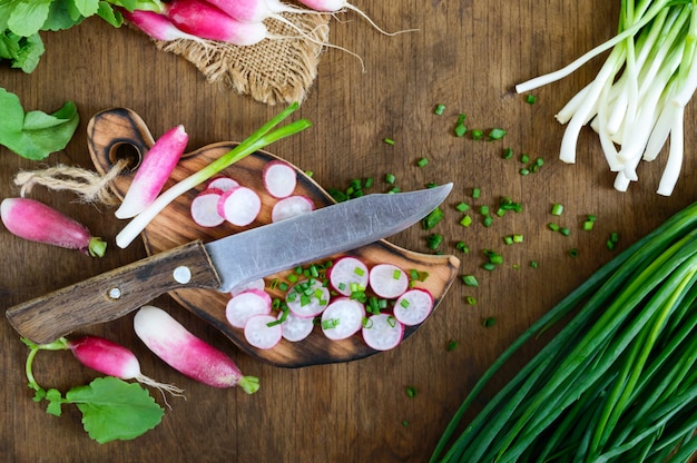 Sliced fresh red radishes and green young onions on white wooden background.  Healthy diet with radish. Ingredients for a light spring vegetable salad. The top view
