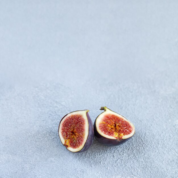 Sliced fresh ripe purple fig on stone table close-up. Square photo with copy space