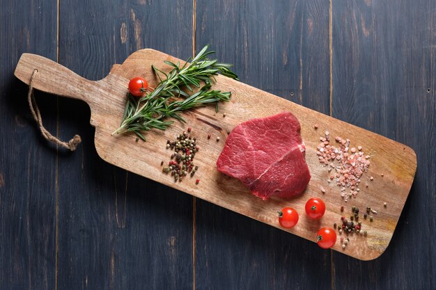 Sliced freshly cooked steak with blood, served on the branches of fresh rosemary on a wooden board